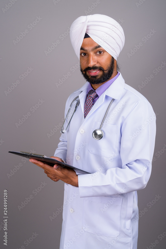 Portrait of young Indian Sikh man doctor holding clipboard Portrait of young Indian Sikh man doctor holding clipboard
