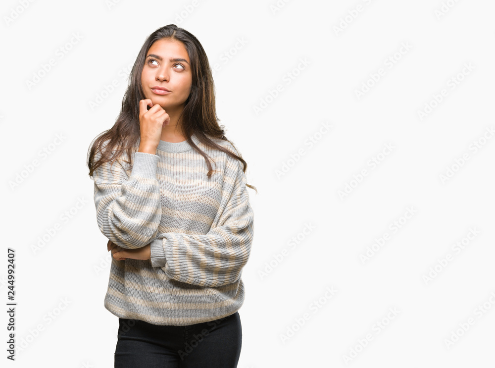 Young beautiful arab woman wearing winter sweater over isolated background with hand on chin thinking about question, pensive expression. Smiling with thoughtful face. Doubt concept. Young beautiful arab woman wearing winter sweater over isolated background with hand on chin thinking about question, pensive expression. Smiling with thoughtful face. Doubt concept.