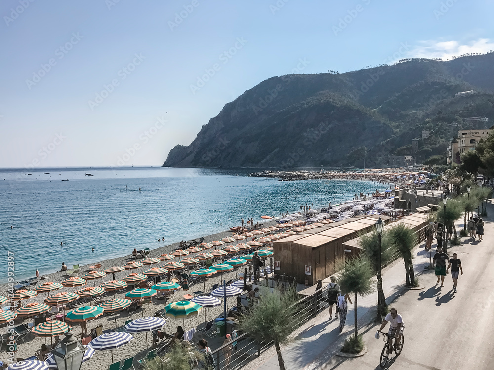 Italy, June 22, 2017: sun loungers and umbrellas on the shoreline of the beach against the backdrop of the mountains