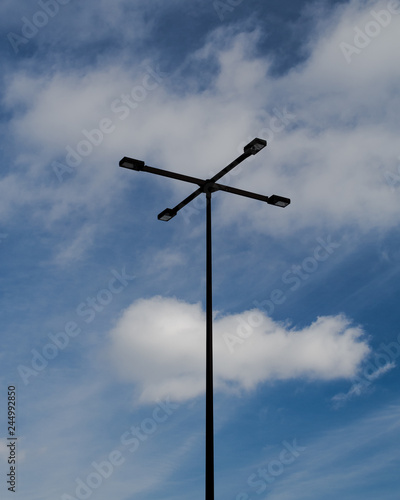 A single lamp pole, with blue sky with clouds