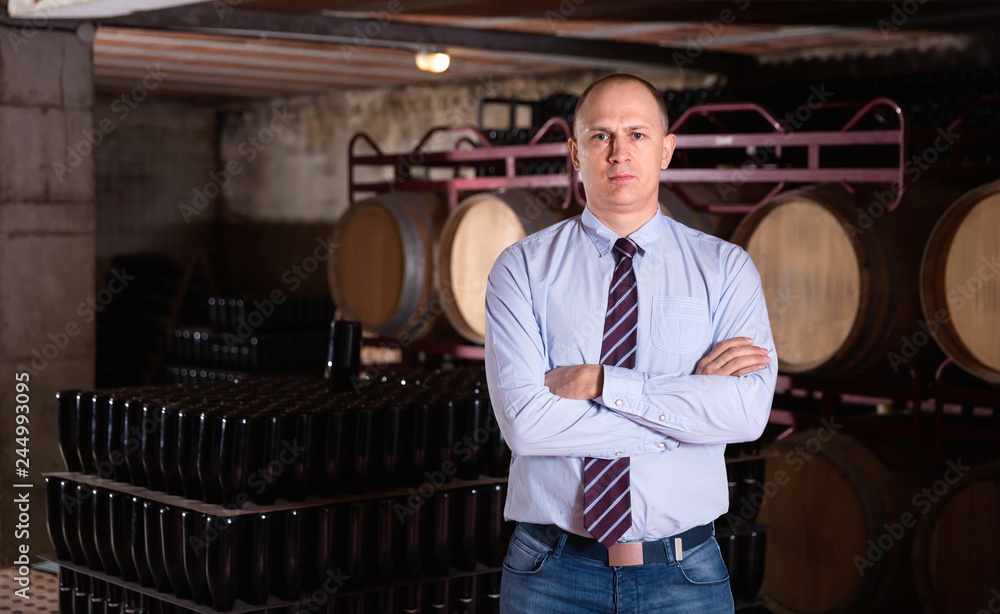 Confident succesful man winemaker posing in own winery vault