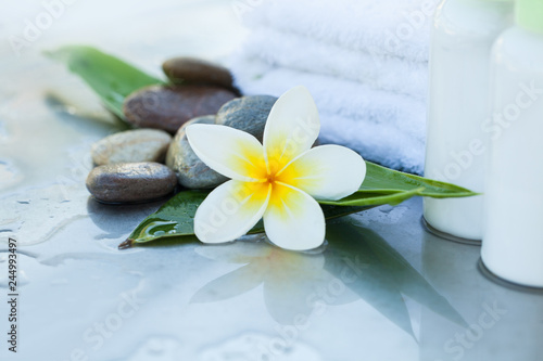 Spa setting with tropical flowers  towel and cream tube. Body care and spa concept