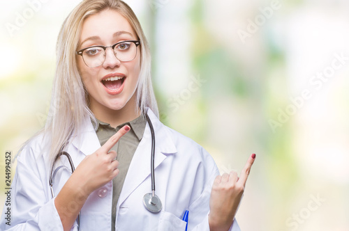 Young blonde doctor woman over isolated background smiling and looking at the camera pointing with two hands and fingers to the side.