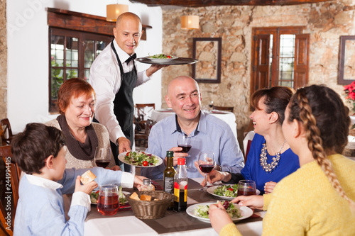 Waiter serving dishes to family