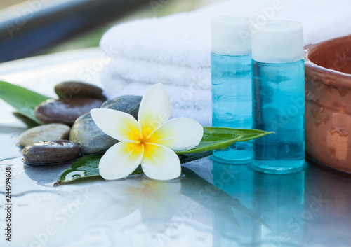 Tropical flower  bowl of water  dark stones  towel and cream tube. Body care and spa concept