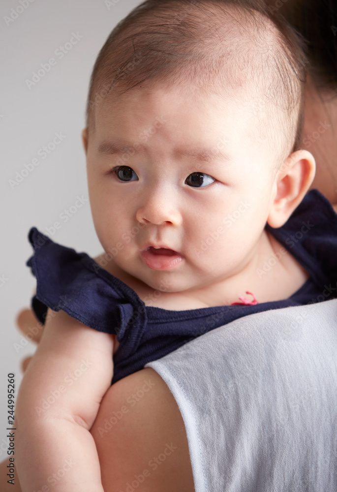 Closeup Asian baby leaning on mother's shoulder Closeup Asian baby leaning on mother's shoulder