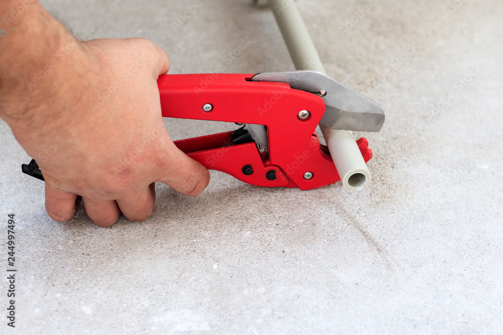 man with red scissors cut pipes for heating, or water. polypropylene mounting system man with red scissors cut pipes for heating, or water. polypropylene mounting system