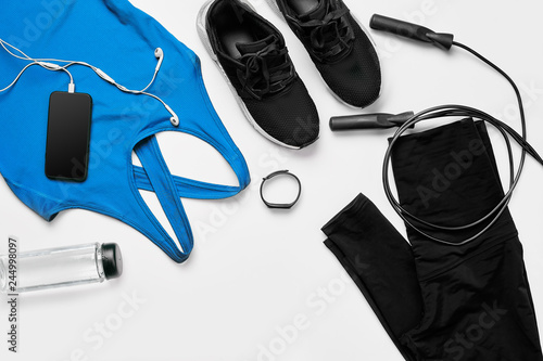 Sport, fitness, healthy lifestyle, cardio training and objects concept - close up of female sports clothing, skipping rope and bottle set