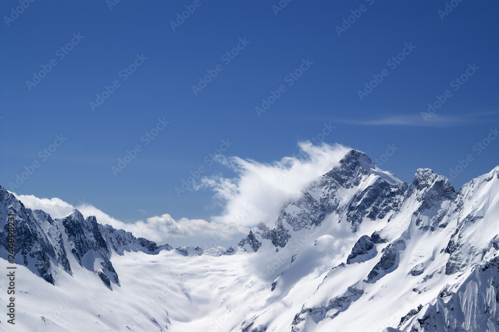 Winter snowy mountains in clouds and beautiful blue sky Winter snowy mountains in clouds and beautiful blue sky