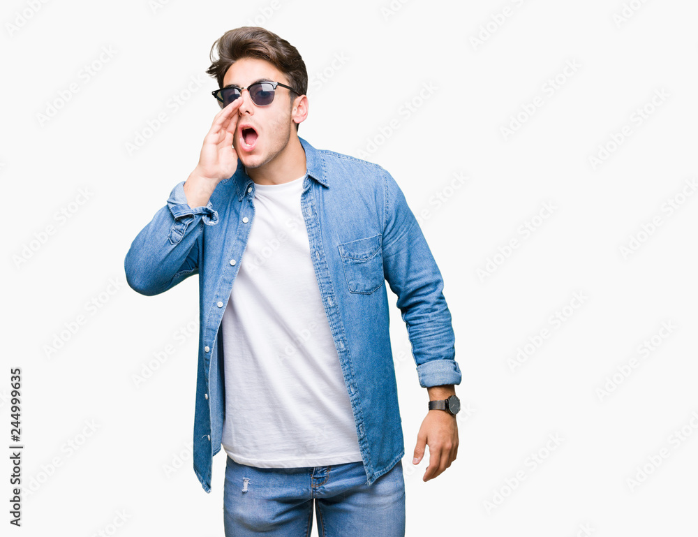 Young handsome man wearing sunglasses over isolated background shouting and screaming loud to side with hand on mouth. Communication concept. Young handsome man wearing sunglasses over isolated background shouting and screaming loud to side with hand on mouth. Communication concept.