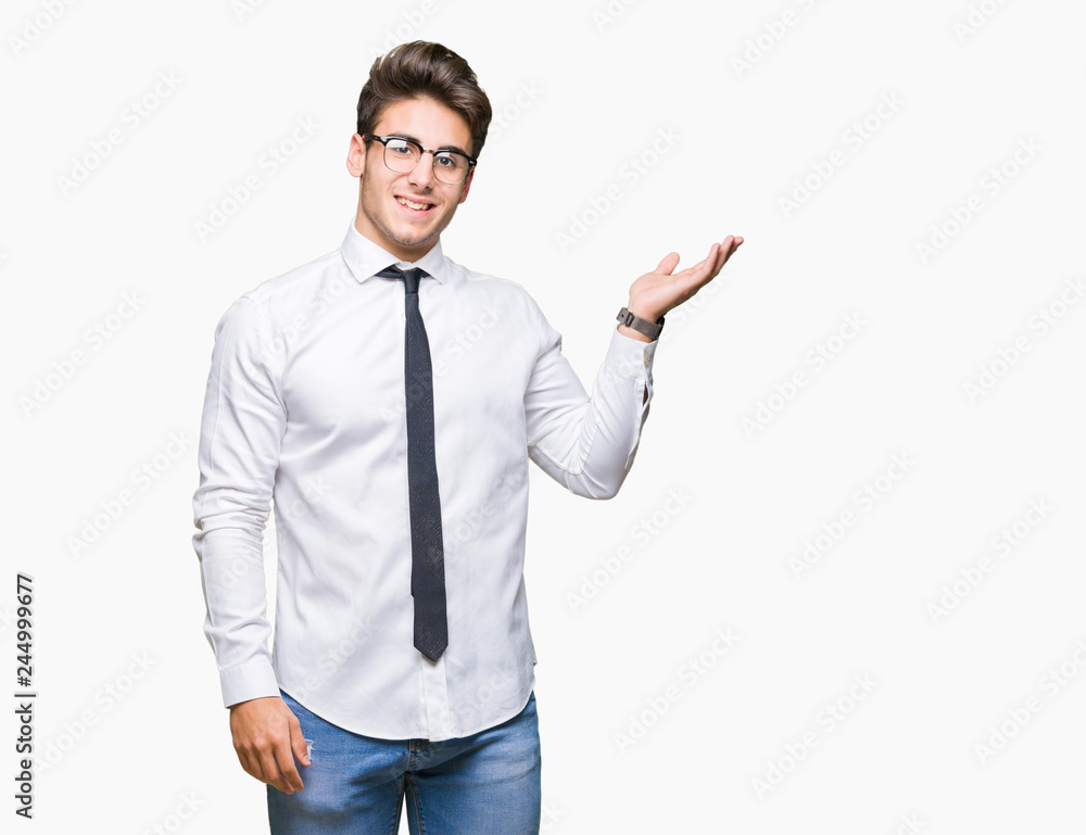 Young business man wearing glasses over isolated background smiling cheerful presenting and pointing with palm of hand looking at the camera. Young business man wearing glasses over isolated background smiling cheerful presenting and pointing with palm of hand looking at the camera.