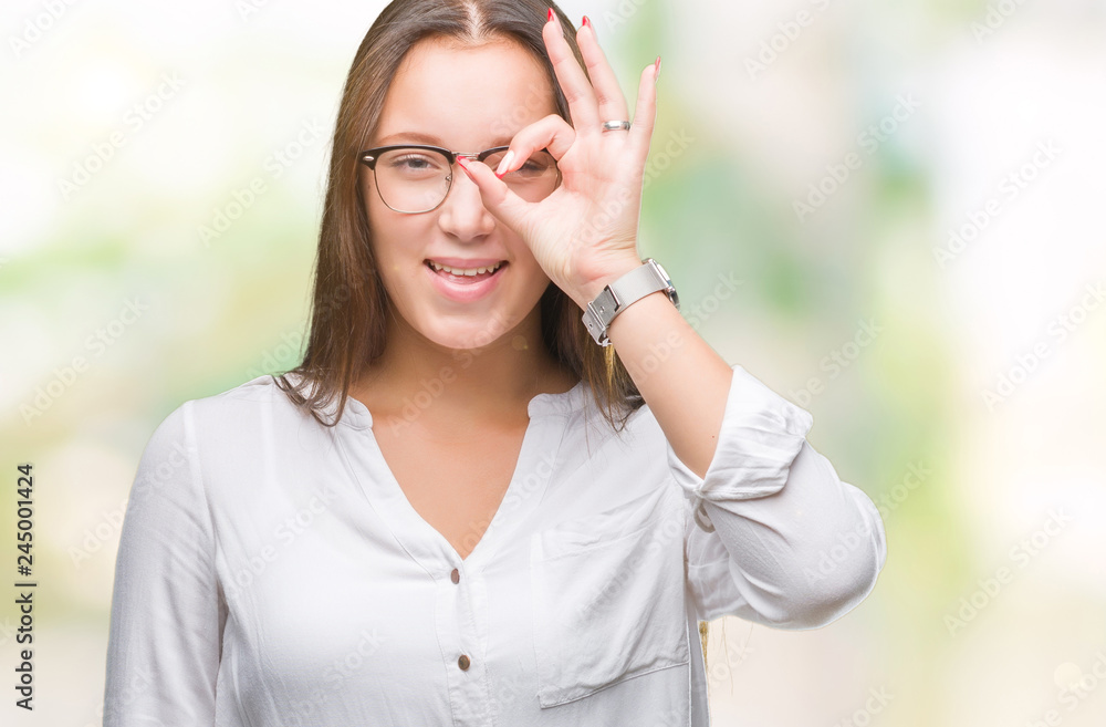 Young caucasian beautiful business woman wearing glasses over isolated background doing ok gesture with hand smiling, eye looking through fingers with happy face. Young caucasian beautiful business woman wearing glasses over isolated background doing ok gesture with hand smiling, eye looking through fingers with happy face.