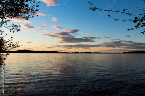 Sunset with dramatic clouds as seen from the shore of a Finish / Scandinavian lake during summer (Finland, Europe)
