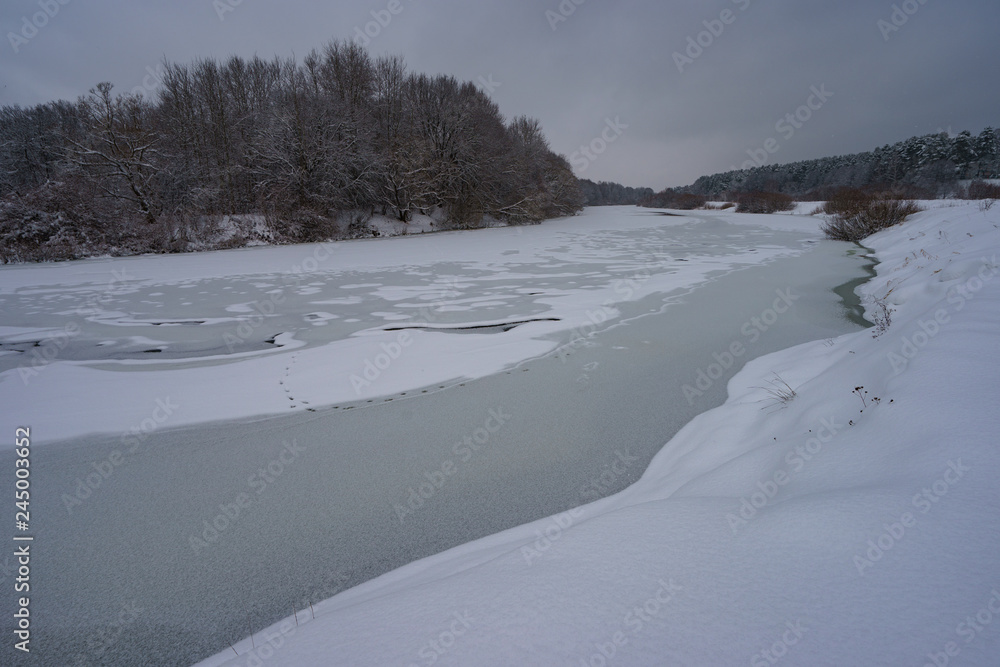 Rural scene at winter time. Image of frozen river and snowy land