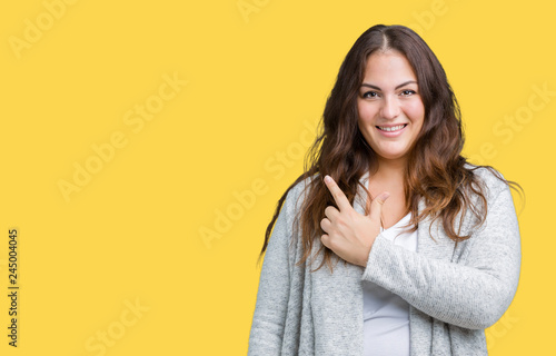Beautiful plus size young woman wearing winter jacket over isolated background cheerful with a smile of face pointing with hand and finger up to the side with happy and natural expression on face © Krakenimages.com