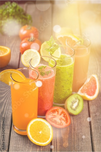 Flasses of various juice with ingredients on wooden table