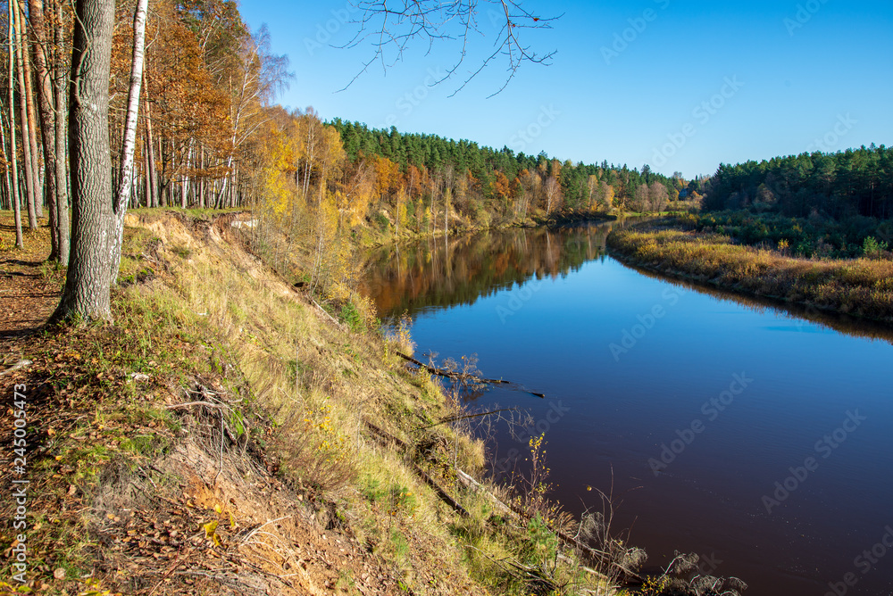 blue sky and clouds reflecting in calm water of river Gauja in latvia in autumn blue sky and clouds reflecting in calm water of river Gauja in latvia in autumn