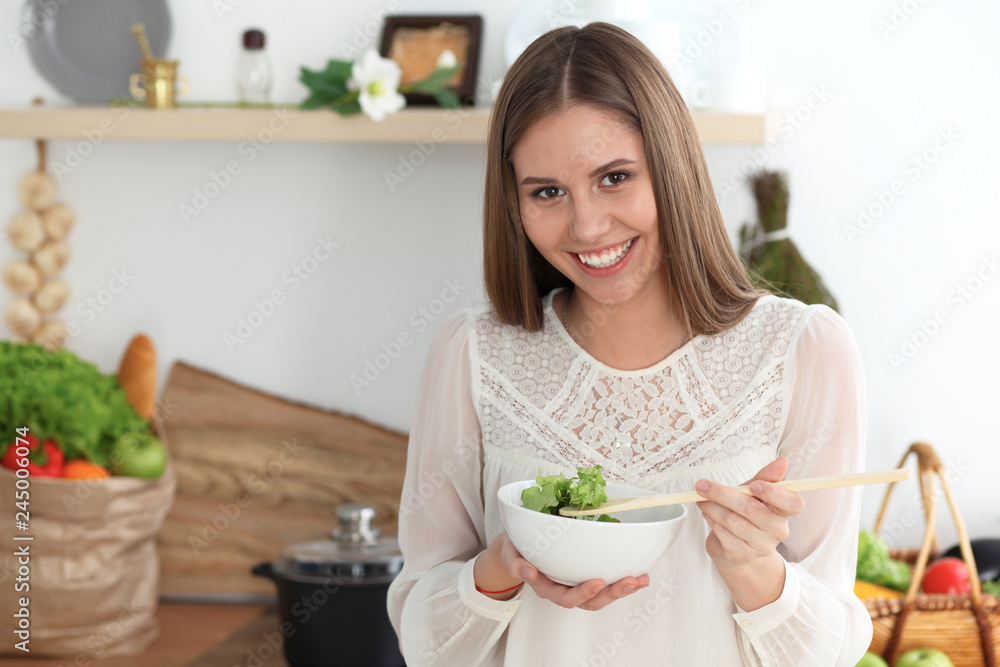 Young happy woman cooking in the kitchen. Healthy meal, lifestyle and culinary concepts. Good morning begins with fresh salad Young happy woman cooking in the kitchen. Healthy meal, lifestyle and culinary concepts. Good morning begins with fresh salad
