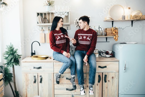 Man and woman hugging in a kitchen and eat sweets on the eve of New Year holidays