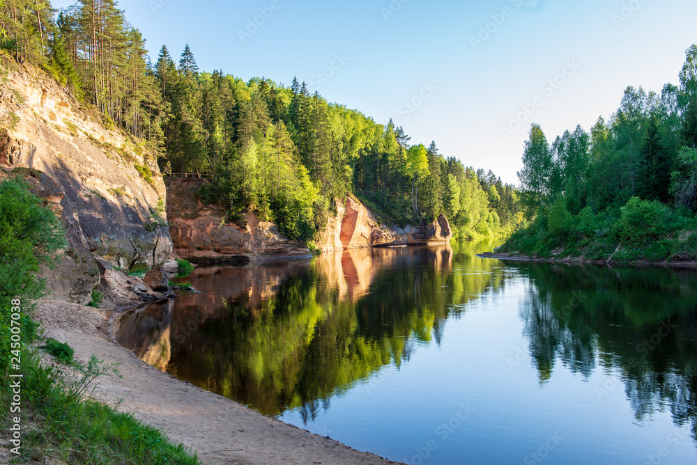 blue sky and clouds reflecting in calm water of river Gauja in latvia in autumn