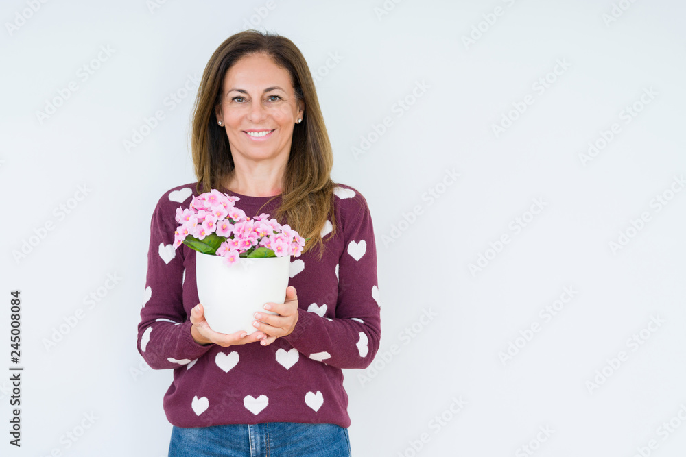 Middle age woman holding flowers pot plant over isolated background with a happy face standing and smiling with a confident smile showing teeth Middle age woman holding flowers pot plant over isolated background with a happy face standing and smiling with a confident smile showing teeth