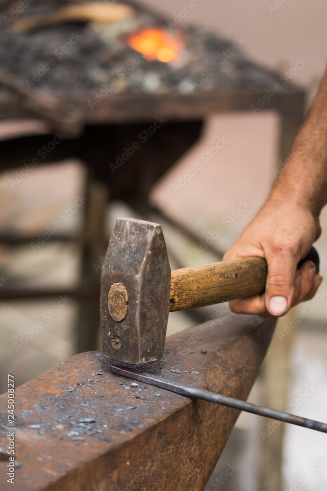 blacksmith working metal with hammer on the anvil in the forge blacksmith working metal with hammer on the anvil in the forge