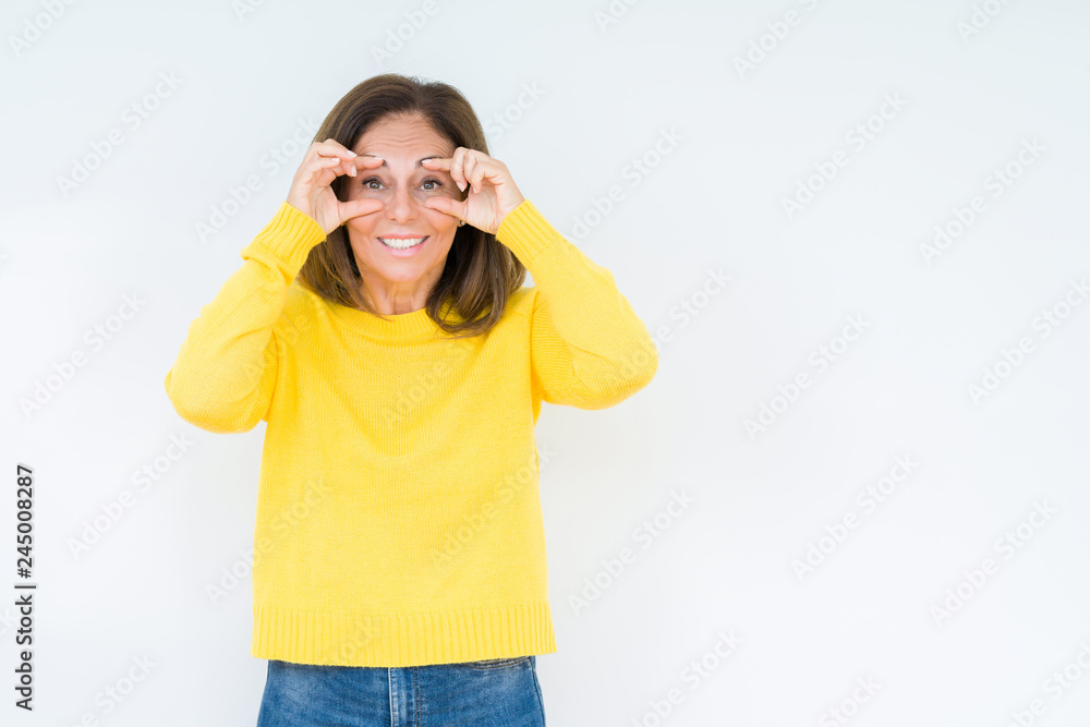 Beautiful middle age woman wearing yellow sweater over isolated background Trying to open eyes with fingers, sleepy and tired for morning fatigue Beautiful middle age woman wearing yellow sweater over isolated background Trying to open eyes with fingers, sleepy and tired for morning fatigue