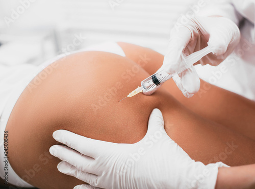 Beautician doing Injection into female buttocks, body mesotherapy photo