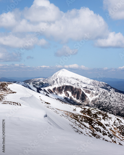 View of the stony hills with snow and blue sky. Dramatic spring scene. Landscape photography