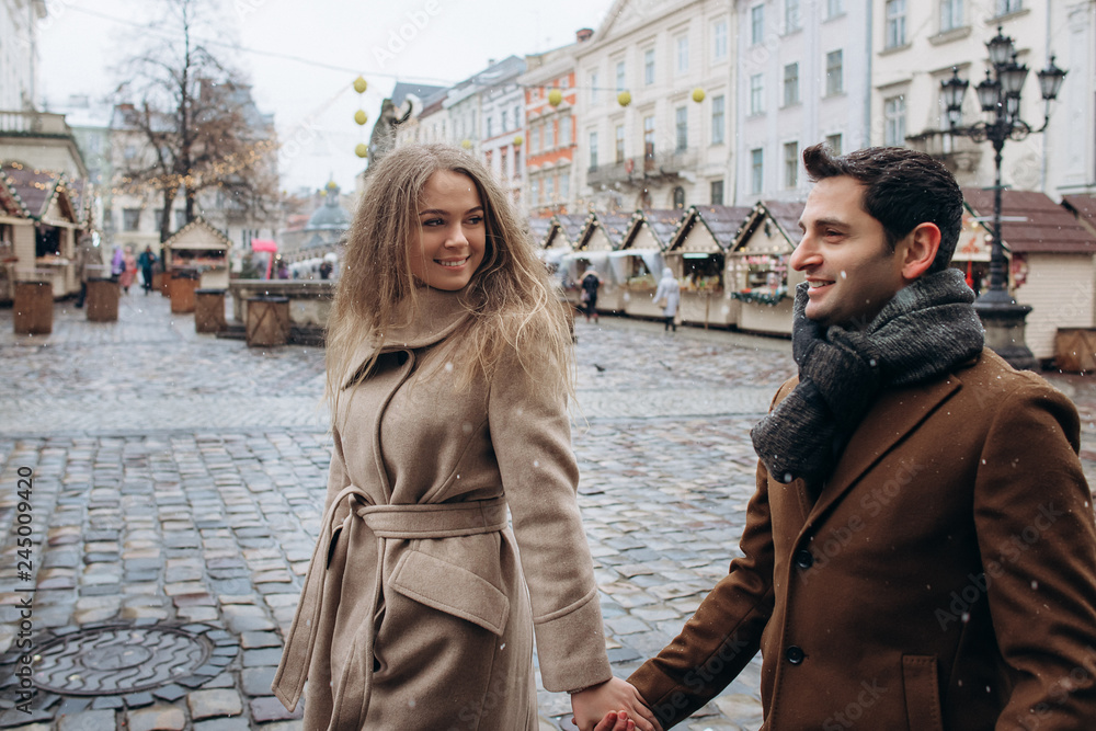 Beautiful lovely couple walking around the central square of the Christmas Europe city