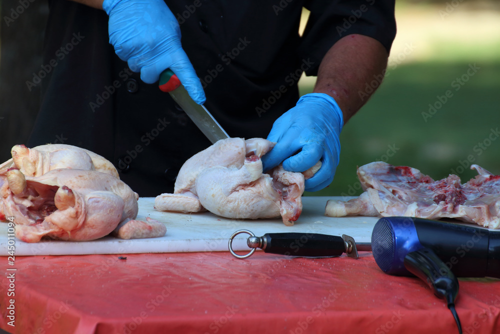 cook cleans a chicken to laze it with spices.