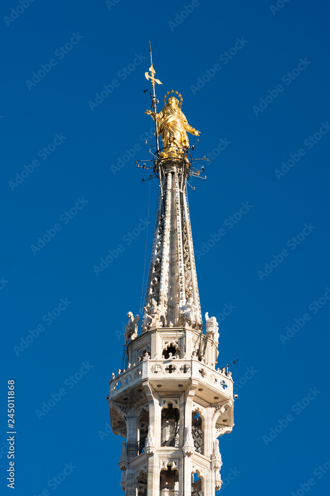 Golden statue of Virgin Mary called Madonnina, placed on the roof of Duomo cathedral, is the symbol of Milan, Italy Golden statue of Virgin Mary called Madonnina, placed on the roof of Duomo cathedral, is the symbol of Milan, Italy