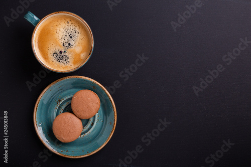 Blue cup of coffee and macaroons on the dark wooden table. Coffe break. Top view. Flat lay
