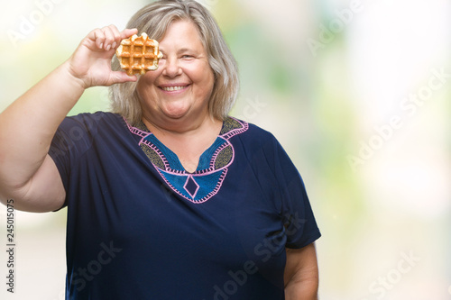 Senior plus size caucasian woman eating waffle over isolated background with a happy face standing and smiling with a confident smile showing teeth