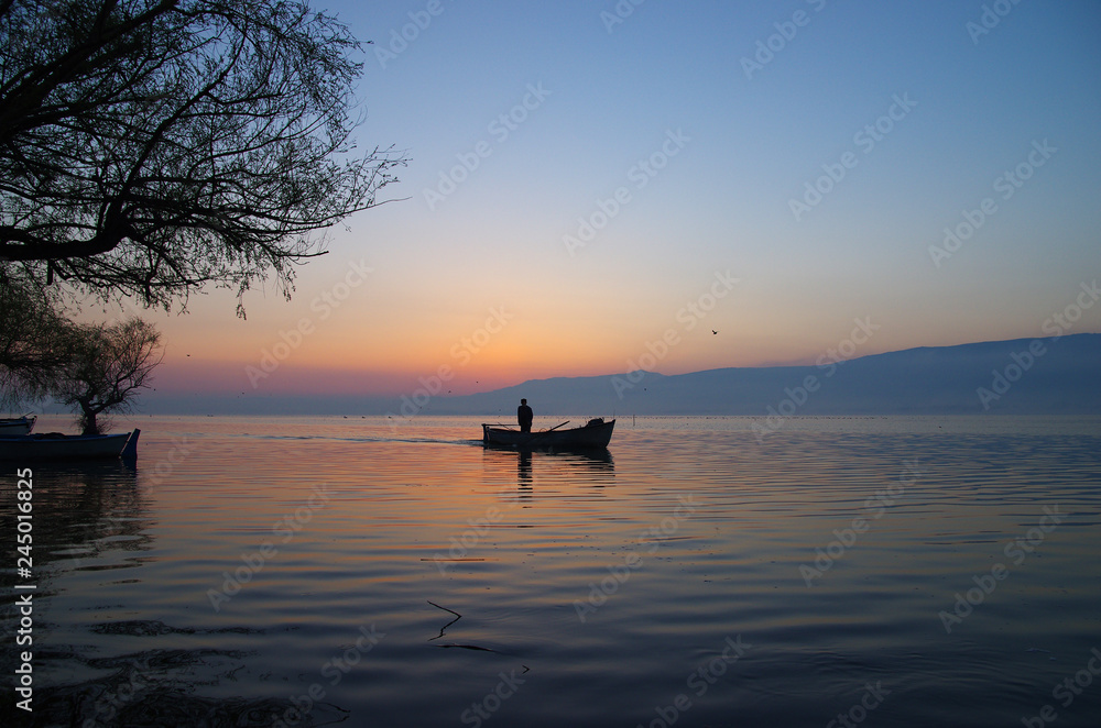 Golyazi, Bursa / Turkey - March 15 / 2014 : Silhouette of a fisherman staning on his boat while sunrise in the morning