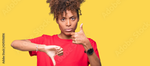Beautiful young african american woman over isolated background Doing thumbs up and down, disagreement and agreement expression. Crazy conflict