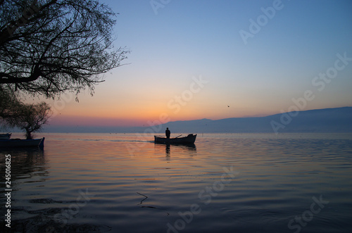 Golyazi, Bursa / Turkey - March 15 / 2014 : Silhouette of a fisherman staning on his boat while sunrise in the morning