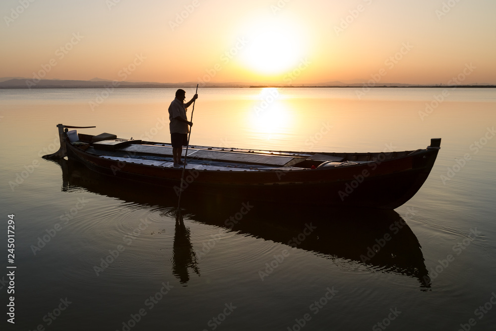 Silhouette of fisherman on a boat at sunset