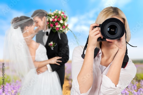 Female photographer holding camera and just married couple on photo