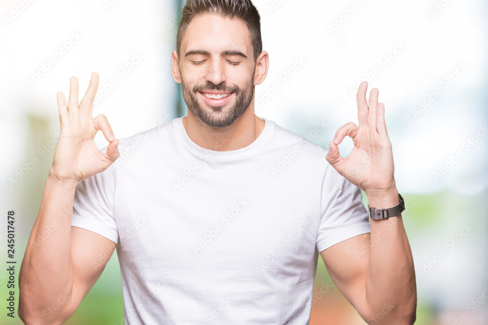 Young man wearing casual white t-shirt over isolated background relax and smiling with eyes closed doing meditation gesture with fingers. Yoga concept. Young man wearing casual white t-shirt over isolated background relax and smiling with eyes closed doing meditation gesture with fingers. Yoga concept.