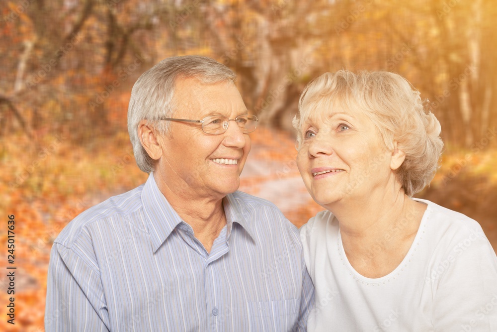 Close-up portrait of an elderly couple hugging in park Close-up portrait of an elderly couple hugging in park