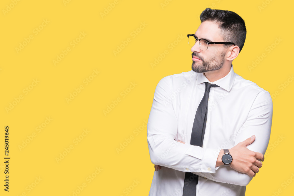 Young handsome business man wearing glasses over isolated background smiling looking to the side with arms crossed convinced and confident Young handsome business man wearing glasses over isolated background smiling looking to the side with arms crossed convinced and confident