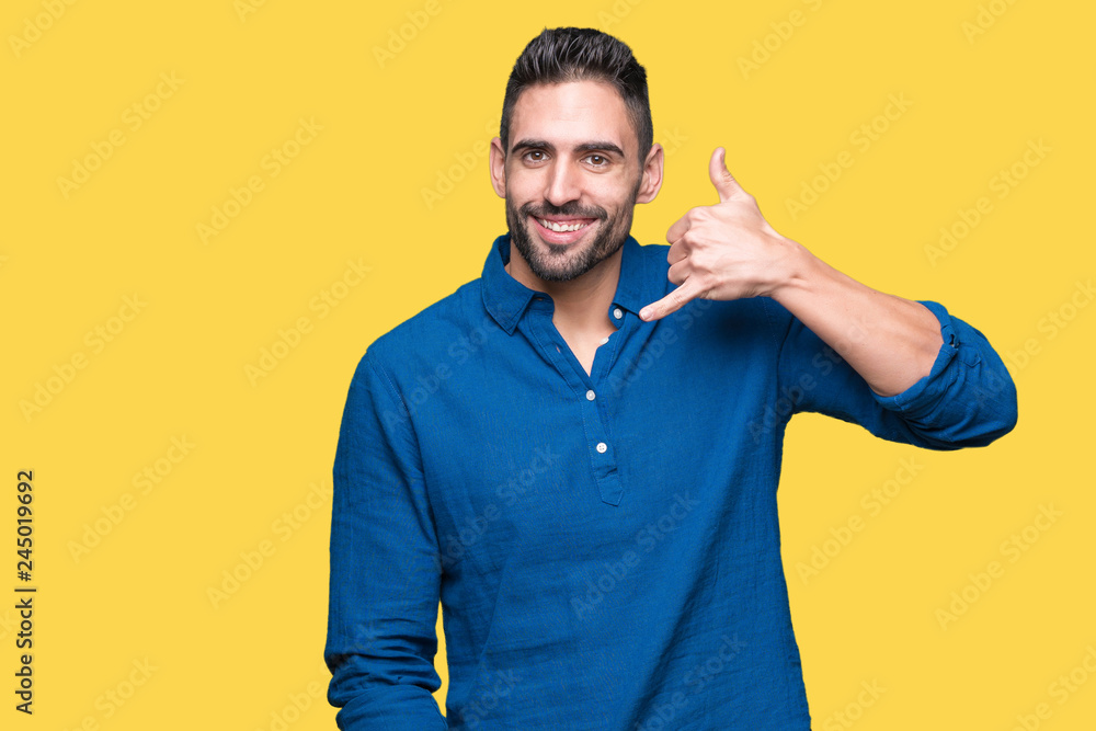 Young handsome man over isolated background smiling doing phone gesture with hand and fingers like talking on the telephone. Communicating concepts. Young handsome man over isolated background smiling doing phone gesture with hand and fingers like talking on the telephone. Communicating concepts.