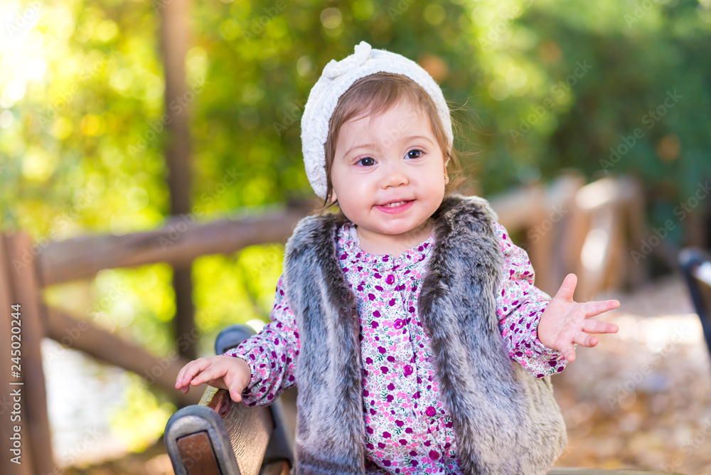 Little kid girl standing in a chair and smiling outdoors. Little kid girl standing in a chair and smiling outdoors.