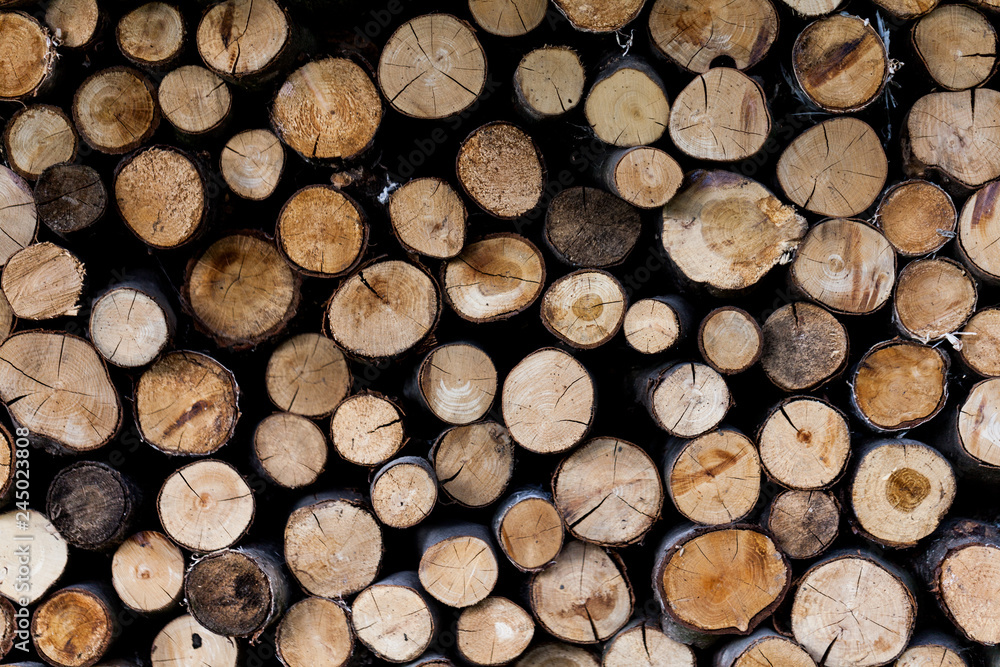 Background of dry chopped firewood logs stacked up on top of each other in a pile.