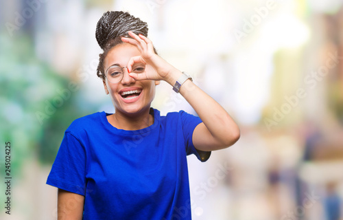 Young braided hair african american girl wearing glasses over isolated background doing ok gesture with hand smiling, eye looking through fingers with happy face.