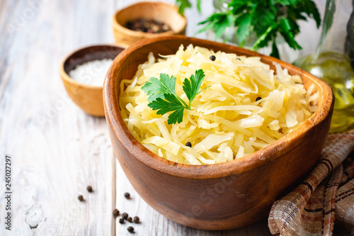Fotografie Homemade sauerkraut with black pepper and parsley in wooden bowl on rustic background
