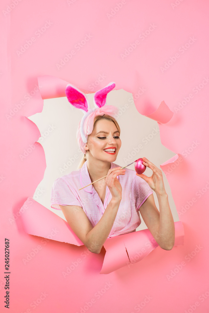Happy easter! Happy bunny woman painting egg. Easter concept. Easter egg ideas. Painting eggs. Sale. Discount. Easter egg decorating ideas. Woman through paper. Pin up girl. White rabbit.