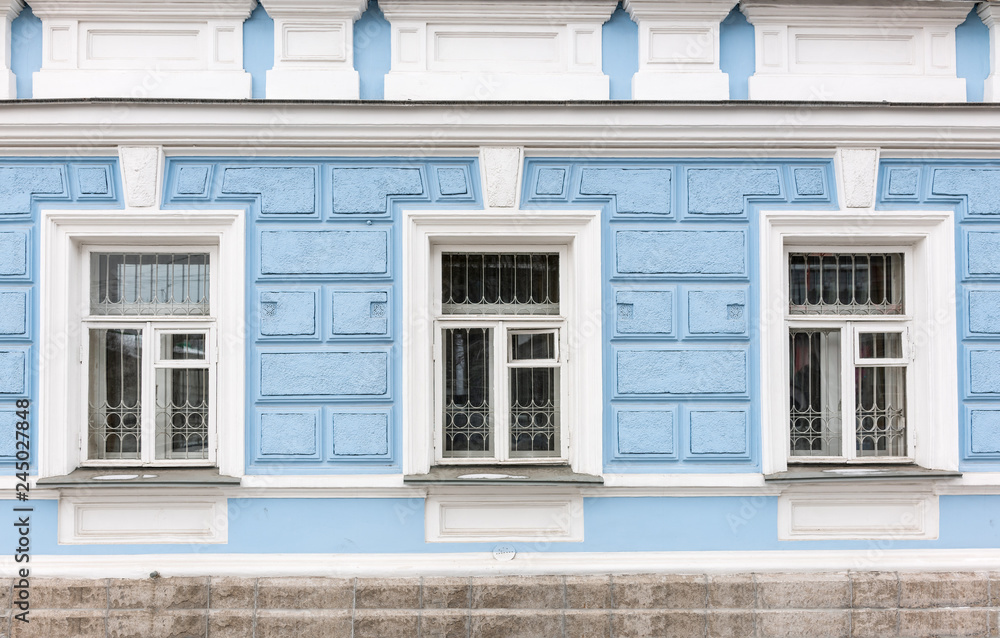 Three windows of the old 19th century mansion with blue walls