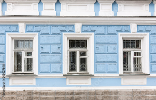 Three windows of the old 19th century mansion with blue walls